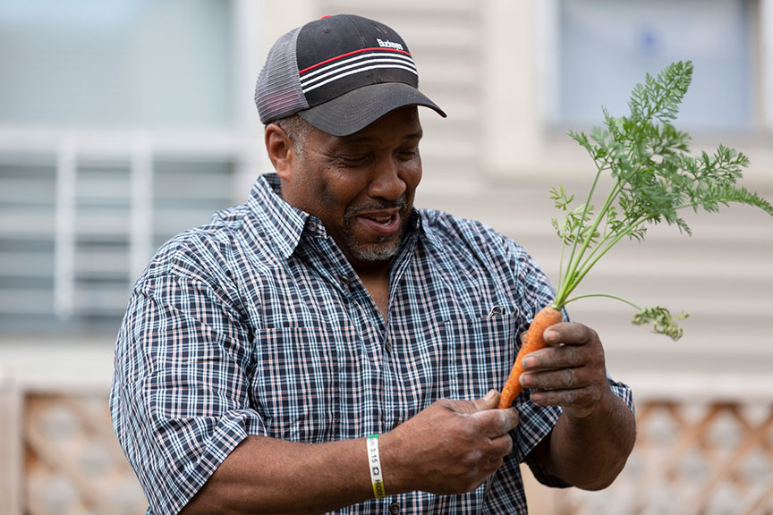 Aaron holding a carrot at the community garden