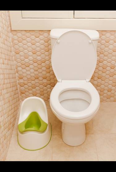 Green potty chair beside a toilet