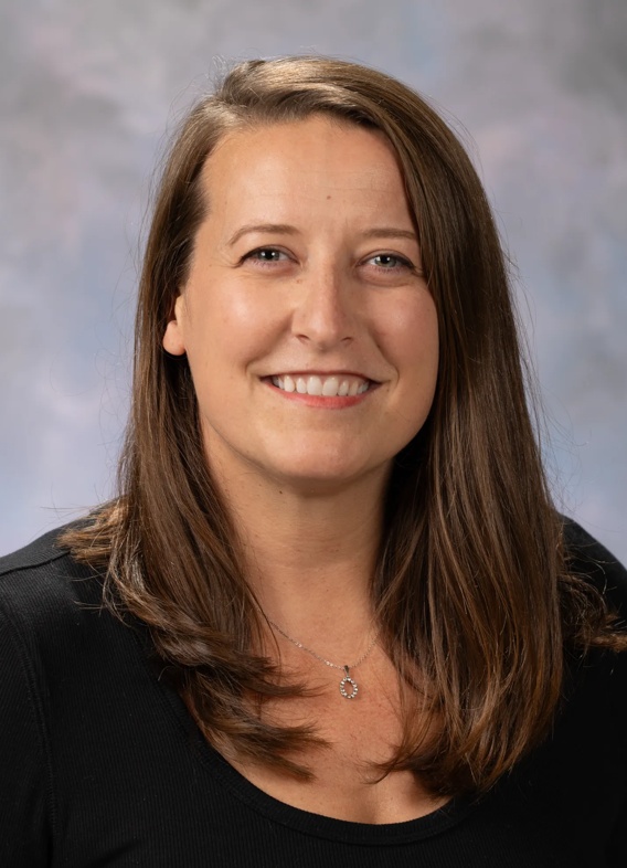 Portrait of Samantha Boch. Dr. Boch has long brown hair with a black top.