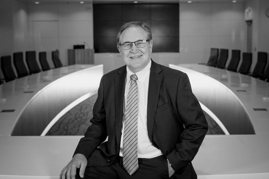 Tim Robinson, smiling and seated with a board room behind him.